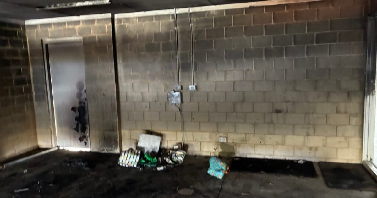 Fire damage, before Garage interior blackened with soot and char across the block walls and ceiling after a fire